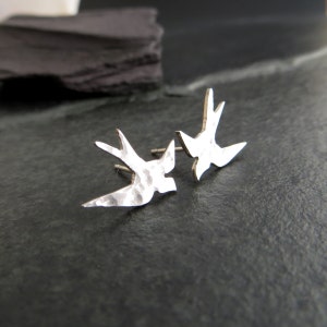 Peut inclure: Une paire de boucles d'oreilles en argent martel&eacute; en forme d'hirondelle. Les boucles d'oreilles sont en forme d'hirondelle en vol.