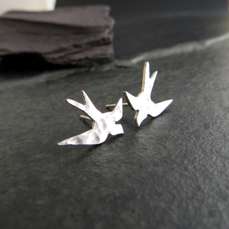 Peut inclure: Une paire de boucles d'oreilles en argent martel&eacute; en forme d'hirondelle. Les boucles d'oreilles sont en forme d'hirondelle en vol.