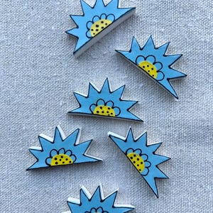 May include: Five ceramic blue and yellow sunburst shapes with black outlines. Each shape has a yellow center with black polka dots.
