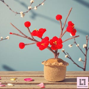 May include: A handcrafted crochet bonsai tree with vibrant red flowers and brown branches, set in a beige crochet pot. The background features a light blue wall and wooden surface, with scattered petals.