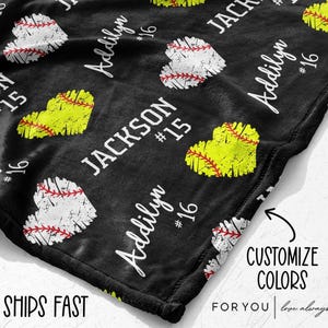 May include: Black blanket with a pattern of baseball and softball hearts. The blanket features the names "Jackson" and "Addilyn" with the numbers "15" and "16". The text "Customize Colors" is also visible.