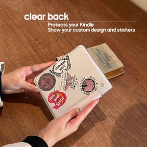 May include: A clear back Kindle case with stickers. The case has the text "clear back, Protects your Kindle, Show your custom design and stickers". The stickers include "DARK ROMANCE", "Hot and Spicy", and "MIDNIGHT BOOK CLUB".