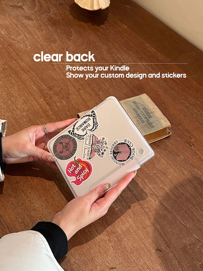 May include: Clear back Kindle case with stickers. The case has the text "clear back" and "Protects your Kindle Show your custom design and stickers". The stickers include "Hot and Spicy", "Dark Romance", and "Midnight Readers Book Club".