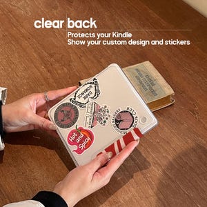 Puede incluir: Una funda transparente para Kindle con pegatinas. La funda tiene una parte trasera transparente y est&aacute; decorada con varias pegatinas, incluida una que dice "Hot and Spicy". Tambi&eacute;n se ve el texto "clear back" y "Protects your Kindle".