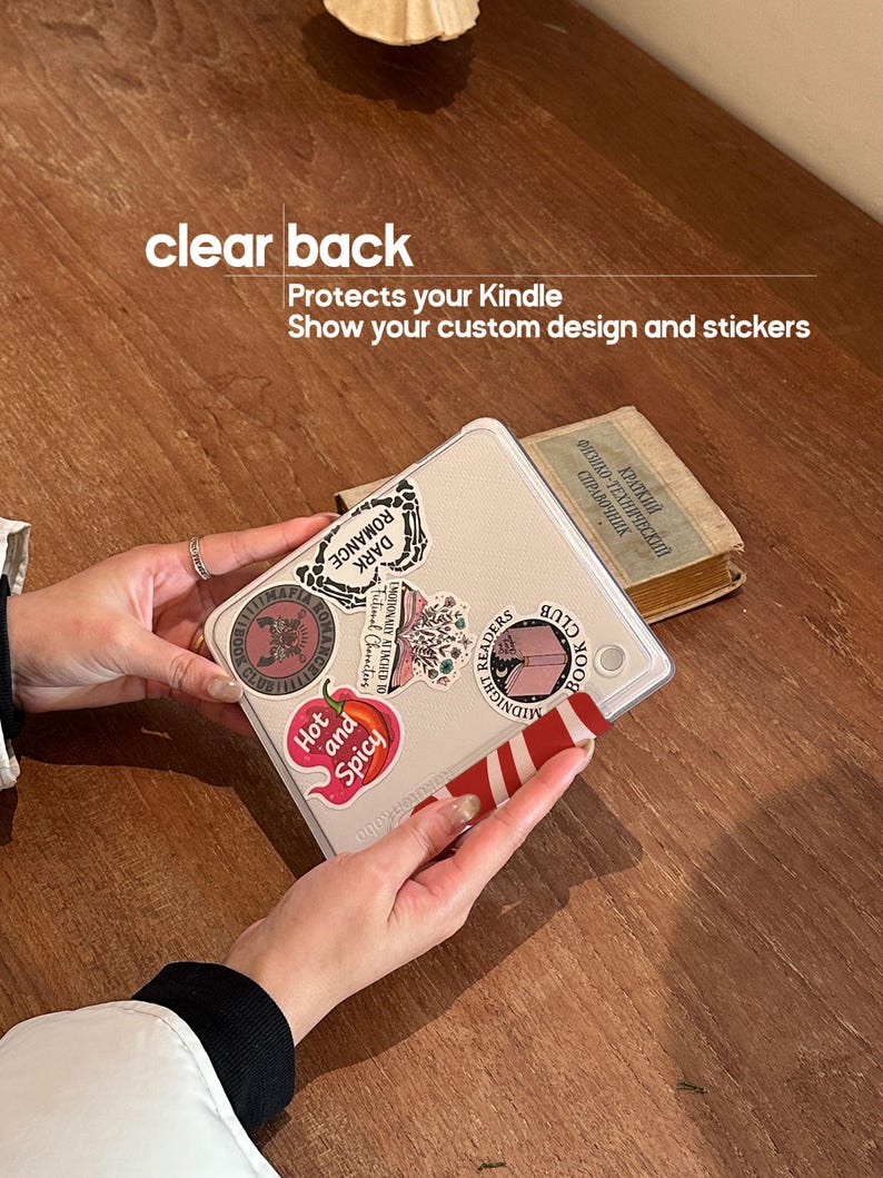 Puede incluir: Una funda transparente para Kindle con pegatinas. La funda tiene una parte trasera transparente y est&aacute; decorada con varias pegatinas, incluida una que dice "Hot and Spicy". Tambi&eacute;n se ve el texto "clear back" y "Protects your Kindle".