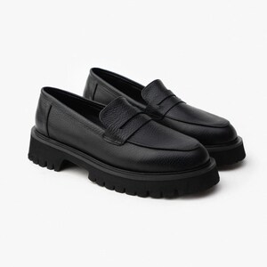 May include: A pair of black leather loafers with a chunky, lugged sole. The shoes have a classic penny loafer design with a rounded toe and a textured leather upper. The soles are thick and provide a rugged look.