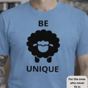 May include: Light blue t-shirt with a black sheep graphic and the words "BE UNIQUE". The shirt also has the text "For the ones who never fit in". This tee is a casual wear item.