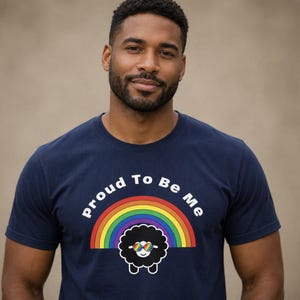 May include: Navy blue t-shirt with the text "Proud To Be Me" above a rainbow and a black sheep wearing sunglasses. The shirt is a crew neck and has short sleeves.