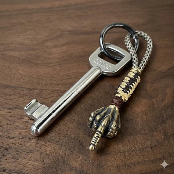 A handmade paracord keychain with a brass skeleton hand flipping the bird — genuinely handcrafted EDC attitude in your pocket.