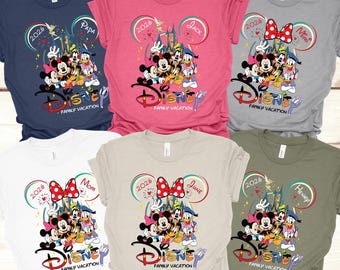 May include: Assorted-color Disney Family Vacation t-shirts. Each shirt features a Disney character graphic with the text "Disney Family Vacation" and a family member's name. The shirts are available in various colors, including navy, pink, gray, white, tan, and olive green.