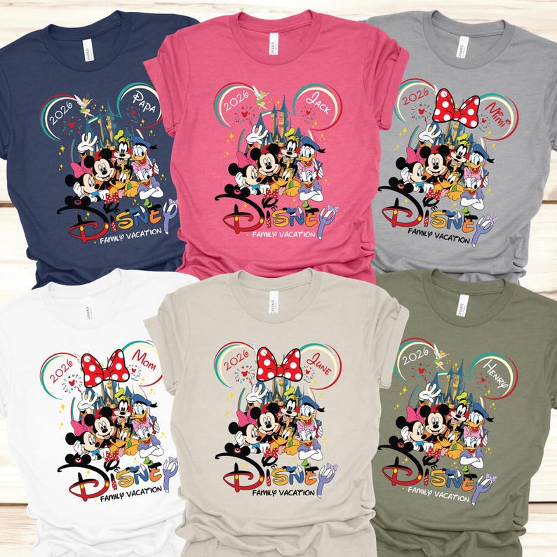 Puede incluir: Varias camisetas de Disney Family Vacation en varios colores. Cada camiseta presenta un gr&aacute;fico de personajes de Disney, el texto "Disney Family Vacation" y el nombre de un miembro de la familia. Las camisetas est&aacute;n disponibles en azul marino, rosa, gris, blanco, beige y verde oliva.