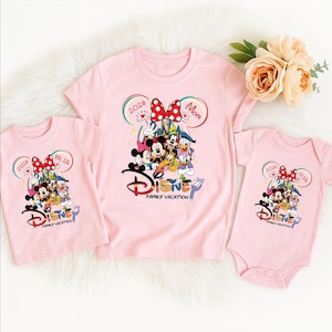 Puede incluir: Camisetas rosas y un body con un dise&ntilde;o de vacaciones familiares de Disney. Las camisetas tienen un gr&aacute;fico de Mickey Mouse, Minnie Mouse y otros personajes de Disney. El texto incluye "2026" y "Mam&aacute;".