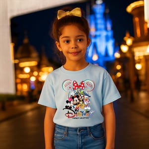 Puede incluir: Camiseta azul claro con un dise&ntilde;o de Disney Family Vacation. El gr&aacute;fico incluye a Mickey y Minnie Mouse, el Pato Donald y Goofy. La camiseta tiene el texto "2026" y "Alicia".