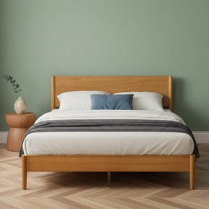 May include: A wooden bed frame with a headboard and footboard. The bed is made of light-colored wood and has a white comforter, a gray blanket, and a blue pillow. The bed is in a bedroom with a green wall.