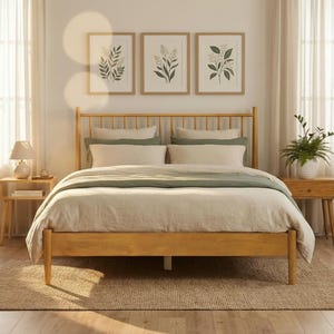 May include: A light wood bed frame with a headboard and footboard. The bed is made up with white and green bedding. Two matching nightstands flank the bed, each with a lamp and decor. Three framed botanical prints hang above the bed.