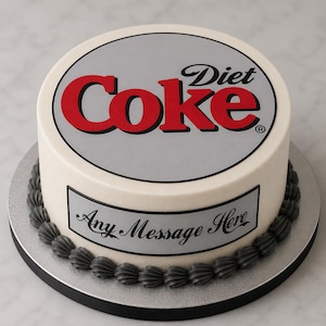 May include: A round cake with smooth white frosting, featuring a large Diet Coke logo on top in red and silver. A rectangular silver plaque on the side displays the text Any Message Here in black script. The base is bordered by dark grey piping.