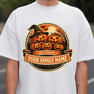 Może przedstawiać: Biały t-shirt z okrągłą grafiką przedstawiającą cztery dynie, z których jedna nosi kapelusz czarownicy, na tle księżyca i nietoperzy. Baner u dołu zawiera napis Est. [Year] oraz YOUR FAMILY NAME.