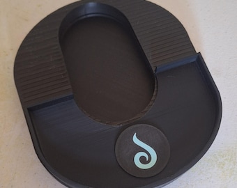 Peut inclure: Un plateau en plastique noir au design en forme de U, doté d'une découpe ovale centrale, de sections latérales striées et d'un emblème circulaire sur la surface avant affichant un motif de tourbillon bleu clair. Finition mate et lisse.