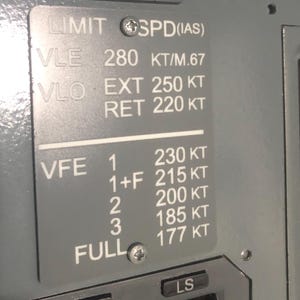 May include: A gray metal placard with white text detailing aircraft speed limits. It lists VLE 280 KT/M.67, VLO EXT 250 KT, VLO RET 220 KT, and VFE settings 1 through FULL with corresponding speeds from 230 KT to 177 KT. The plate is secured by two screws.