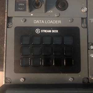 Peut inclure: Un panneau de contrôle Stream Deck noir doté de quinze boutons carrés est monté sur un panneau de cockpit d'avion gris. Le panneau affiche le texte DATA LOADER au-dessus de l'appareil, avec des étiquettes OPEN, FAULT, LOCK et GEAR visibles.