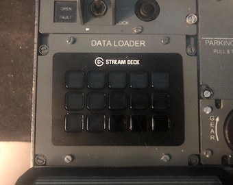 May include: A black Stream Deck control panel with fifteen square buttons is mounted on a grey aircraft cockpit panel. The panel features the text DATA LOADER above the device, with additional labels including OPEN, FAULT, LOCK, and GEAR visible nearby.