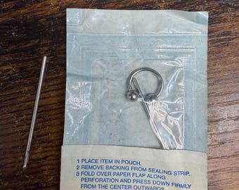 Conjunto para piercing de cartilagem no septo, com barra em ferradura de aço cirúrgico 14G e agulha de perfuração.