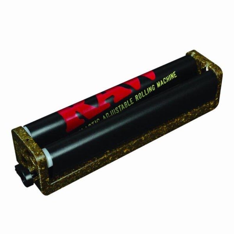 May include: A RAW adjustable rolling machine featuring a textured, speckled brown frame and two black rollers. The top roller displays the red RAW logo and the text "ADJUSTABLE ROLLING MACHINE" in yellow lettering against a black background.