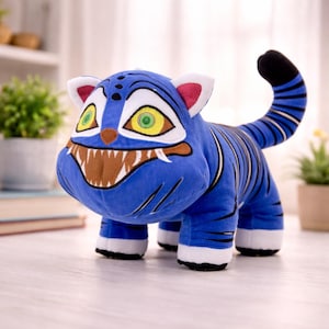 Könnte beinhalten: Ein blaues Tiger-Plüschtier mit schwarzen Streifen, weißen Pfoten und einem schwarzspitzigen Schwanz. Der Tiger hat ein breites Grinsen mit braunen Zähnen, gelben Augen und weißen und rosa Ohren. Ein skurriles Stofftier.