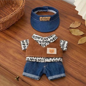 Puede incluir: Un conjunto para beb&eacute; que incluye una visera vaquera con la palabra "BABY" bordada, un chaleco de pana marr&oacute;n y un conjunto de pantalones cortos vaqueros. El chaleco tiene un parche de oso y est&aacute; superpuesto a una camisa con un patr&oacute;n de texto repetido.
