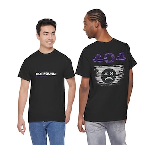 Op de afbeelding: Zwarte T-shirts met witte en paarse afbeeldingen. Eén shirt toont "NOT FOUND." in witte tekst. Het andere heeft een paars "404" ontwerp en een trieste gezichtsafbeelding op de rug. De shirts zijn korte mouwen.