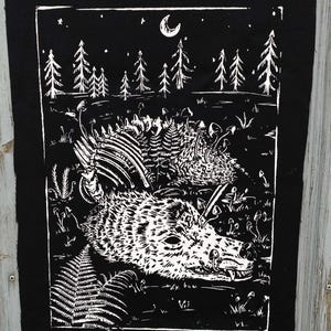 Könnte beinhalten: Schwarz-weißer Aufnäher mit einer detaillierten Illustration eines Wolfs in einer Waldszene. Das Design umfasst Bäume, Pilze, Farne und einen Halbmond am Nachthimmel. Der Aufnäher hat einen schwarzen Rand.