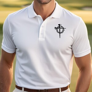 May include: White polo shirt with a black graphic of a cross, nails, and a crown of thorns. The shirt has a classic collar and button-up placket. The short-sleeved shirt is made of a lightweight material.