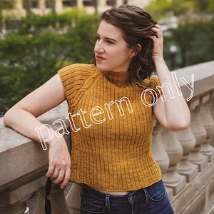 May include: A woman wearing a mustard yellow sleeveless knitted top with a high neck and a ribbed texture. The top is cropped and the woman is wearing blue jeans.