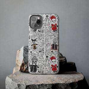 Pode incluir: Capa de telefone branca com um design de rabiscos em preto e vermelho. A capa apresenta personagens de desenhos animados em trajes vermelhos e pretos, juntamente com outros rabiscos. A capa está sobre uma superfície de pedra cinza.