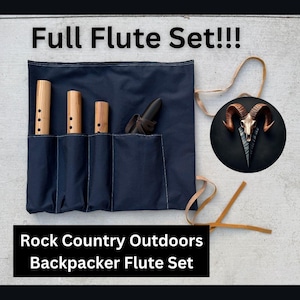 May include: A navy blue canvas flute case with three wooden flutes and a black flute. The case has a leather strap and the text "Full Flute Set!!!" and "Rock Country Outdoors Backpacker Flute Set".