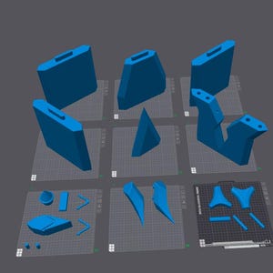 Puede incluir: Colección de componentes azules impresos en 3D, incluyendo formas rectangulares con asas, prismas triangulares y otras formas geométricas. Las piezas están dispuestas sobre una cuadrícula.