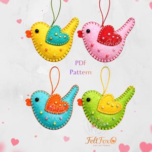 May include: Four felt bird decorations in yellow, pink, blue, and green, each with a heart-shaped accent. The birds have orange beaks and are stitched with contrasting thread. The text "PDF Pattern" is visible. The Felt Fox logo is also visible.
