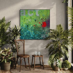 May include: Abstract art piece with the word "ACT" in silver letters. The artwork features a textured surface with shades of green, blue, and red. The painting is framed in black and hangs on a gray wall, surrounded by potted plants and a wooden chair.