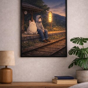 May include: Framed artwork depicting an anime-style scene at a train station. A person in a hoodie sits with a large, white cat. A sign with Japanese text is illuminated by a warm light. The artwork is set against a backdrop of a dusk sky.