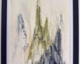 May include: Abstract watercolor painting in a black frame. The artwork features a central mountain-like form in shades of green and brown, with blue and gray accents. The background is a soft, off-white color.