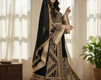 May include: A black and gold embroidered dress with a matching head covering. The dress features intricate patterns and designs, with gold accents on the sleeves and hem. The head covering is a sheer black veil with gold trim.