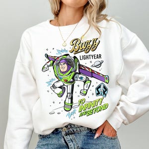 Puede incluir: Una taza de cer&aacute;mica blanca con un asa negra y el texto "But First, Coffee" en negrita negra. La taza se encuentra sobre un fondo borroso, sugiriendo un ambiente acogedor.