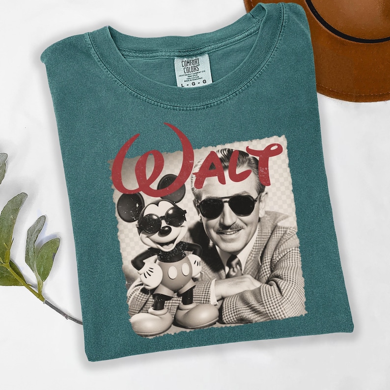 Puede incluir: Camiseta Comfort Colors de color verde azulado con un gr&aacute;fico vintage de Walt Disney y Mickey Mouse con gafas de sol. La palabra "Walt" est&aacute; en escritura roja encima de la imagen. Talla L.