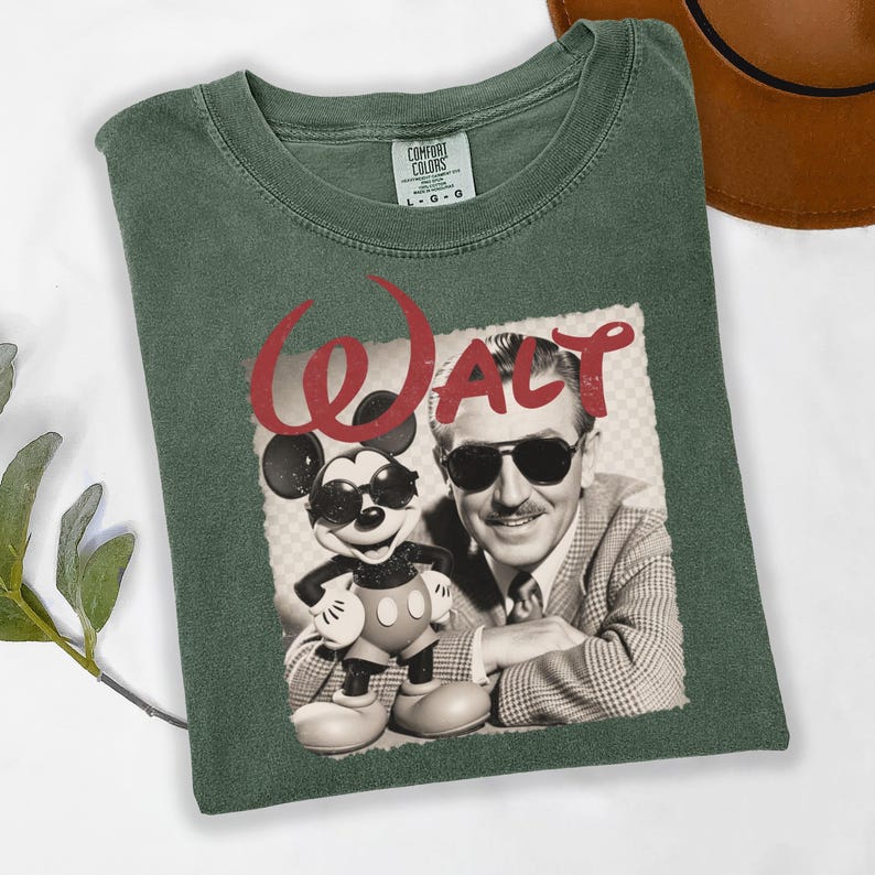 Puede incluir: Camiseta verde con un gr&aacute;fico de Walt Disney y Mickey Mouse con gafas de sol. La palabra "Walt" est&aacute; impresa en rojo encima de la imagen. La camiseta est&aacute; hecha de un material suave y c&oacute;modo.