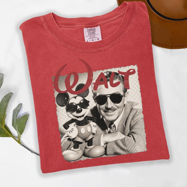 Puede incluir: Camiseta roja con un gr&aacute;fico de Mickey Mouse y Walt Disney con gafas de sol, con el nombre "WALT". La camiseta tiene cuello redondo y una etiqueta Comfort Colors.