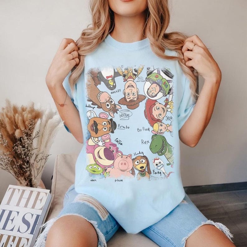Cartoon characters from Toy Story with names in a playful, colorful style on a t-shirt.