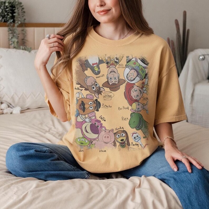 Colorful vintage-style Toy Story characters with names in playful design on a t-shirt.