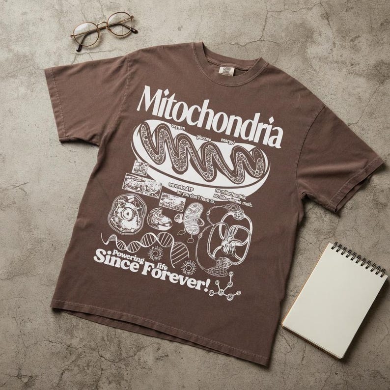 May include: A brown short-sleeve t-shirt featuring a white graphic print of a mitochondrion with the text Mitochondria, Powering life Since Forever!, oxygen, glucose, energy, we make ATP so you don't have to, and no mitochondria, no life-simple math.