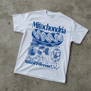 May include: A white short-sleeve t-shirt featuring a blue graphic print of a mitochondrion with the text Mitochondria, oxygen, glucose, energy, we make ATP so you don't have to, no mitochondria no life, simple math, and Powering life Since Forever!