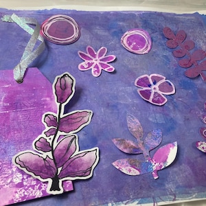 Pode incluir: Desenhos florais e de folhas roxas e brancas sobre um fundo roxo. Os desenhos são recortados e sobrepostos sobre o fundo. Há uma etiqueta roxa com uma fita prateada no lado esquerdo da imagem.